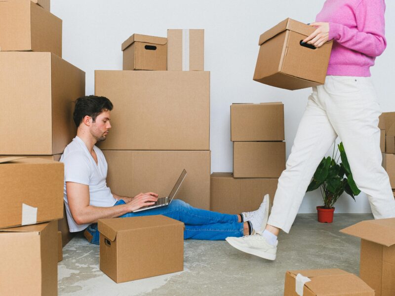man using laptop on the floor while surrounded by boxes